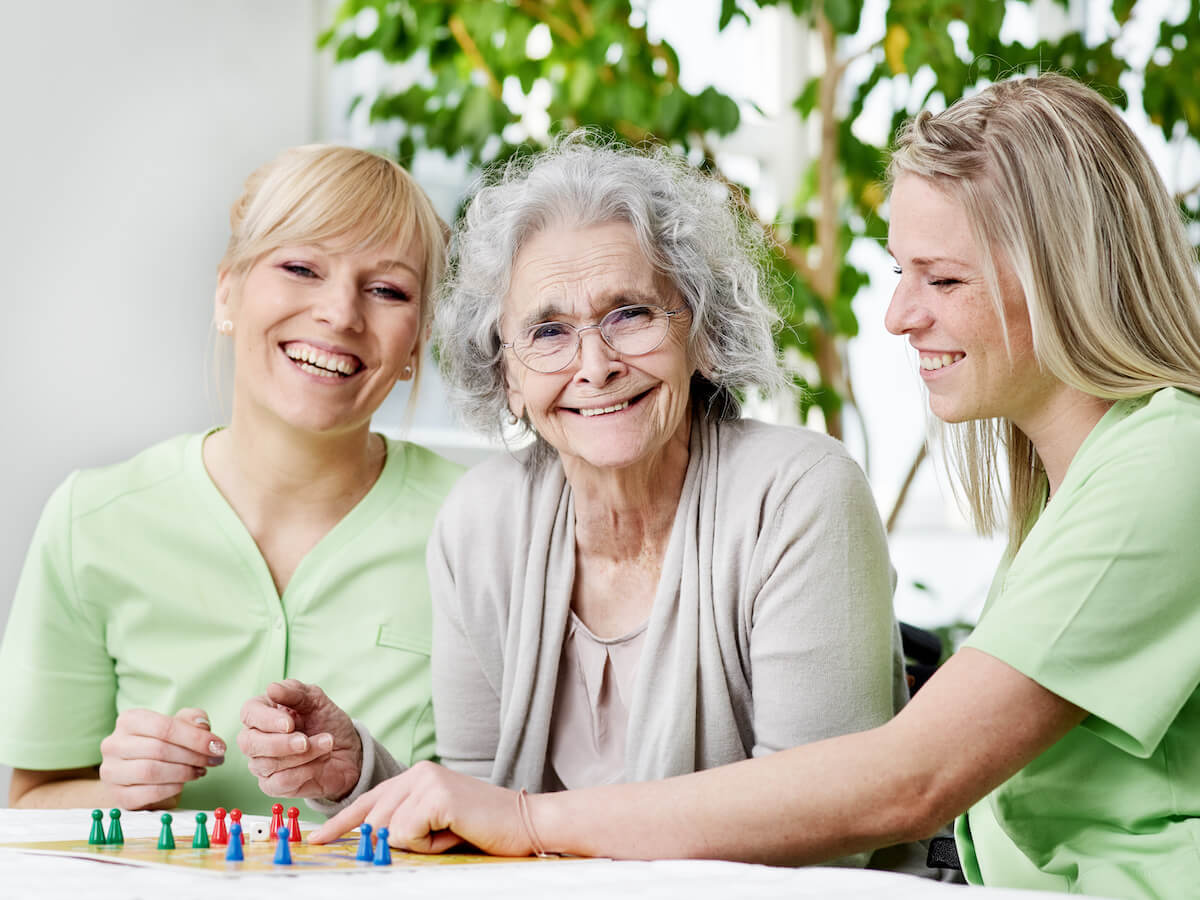 Jasmine Estates of Edmond | Senior woman and her two caregivers playing a game | memory care facilities