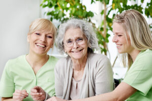Jasmine Estates of OKC | Female caretakers spending time with smiling senior resident